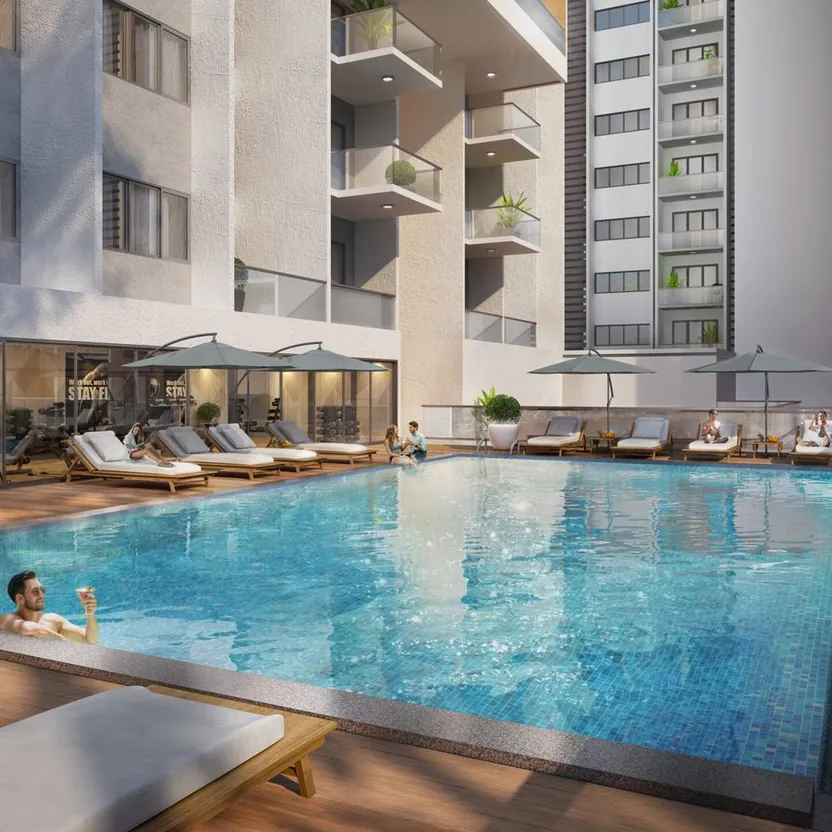 A swimming pool with loungers and umbrellas below the towers of ELV HighGarden